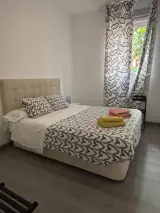 Dormitorio con armario blanco, radiador y puerta abierta a la zona de cocina con microondas